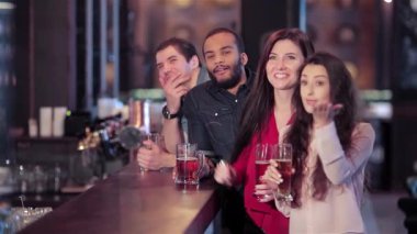 Barda kutlama yapan bir grup genç erkek ve kadın en sevdikleri futbol takımı için tezahürat yaparken kadehlerini kaldırıyorlar. Atmosfer heyecan verici, kahkaha ve arkadaşlıkla dolu. İçkiden ve paylaşımdan hoşlanıyorlar.
