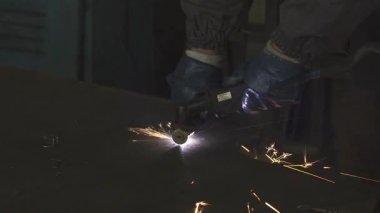 Yakın çekim, yetenekli bir metal işçisini ustalıkla plazma kesiciyle çeliği keserken yakalar ve havaya göz kamaştırıcı kıvılcımlar saçar. Bu yoğun sahne ağır sanayinin ham enerjisini ve hassasiyetini gözler önüne seriyor.