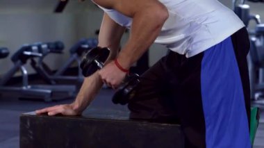 Kafkasyalı bir sporcu modern bir fitness merkezinde yoğun komisyonlar alıyor. Bu yan bakış açısı güçlü, kaslı sarışını bir egzersiz tezgahına yaslanırken kollarını şekillendirirken bağlılığını ve gücünü gösteriyor.