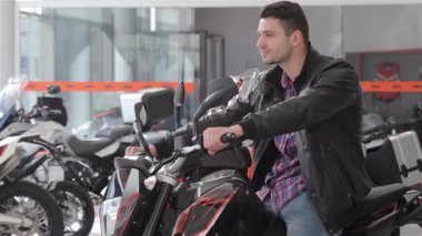 Tarz sahibi beyaz bir adam parlak siyah bir motosiklete güvenerek oturur ve gidonu ustalıkla sola çevirir. Odaklanmış ifadesi, benzin deposuna dokunduğunda heyecanını gözler önüne seriyor. Hayalindeki yolculuğu seçmenin heyecanına dalıyor.