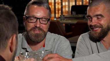 Canlı bir sahne, bir grup olgun adamın lüks bir barda viski bardaklarını tokuşturup, yoldaşlık ve kutlama yaptıkları bir sahneyi çeker. Yumuşak ışıklandırma ve zarif dekor ile vurgulanan ılık ortam, onların kahkahalarını ve çekiciliğini arttırır.