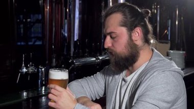 Uzun saçlı sakallı bir adam barda tek başına oturur, yarım litre bira yudumlarken, dalgın dalgın uzaklara bakar. Yüzündeki ifade derin bir hayal kırıklığı ve yalnızlığı yansıtıyor. Şehir yalnızlığının ve ağırlığın özünü yakalıyor.