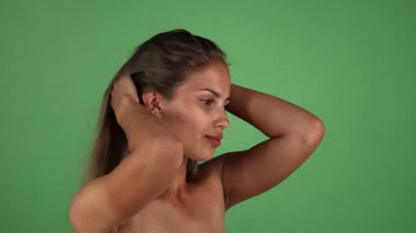 Genç bir kadının büyüleyici portresi zarif bir şekilde dalgalı saçlarıyla canlı yeşil renkli bir arka planda oynuyor. Bu büyüleyici sahne kendine güven ve cazibe yayıyor. Kusursuz cildini gösteriyor ve sağlıklı bir yaşam tarzını somutlaştırıyor.