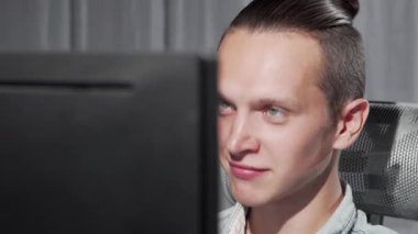 Odaklanmış mavi gözlü genç bir adam canlı bir video çağrısına bağlanıyor, dikkatle bilgisayar ekranına bakıyor. Şık saç stili ve modern çalışma alanı dijital iletişimin özünü vurgulayan davetkar bir atmosfer yaratıyor.