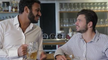İki neşeli genç adam, yoldaşlık ve kutlama ruhunu somutlaştıran canlı bir barda bira bardaklarını kaldırıyor. Canlı atmosfer kahkahalar ve konuşmalarla dolu, dostluğa ve sıcak anılarla çevrili paylaşılan anılara kadeh kaldırırken.