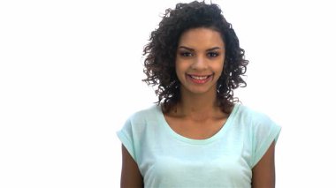 Neşeli genç bir Afro-Amerikalı kadın pozitif ışıldıyor. Parlak, dişlek bir gülümseme sergiliyor. Kıvırcık saçları yüzünü, saf beyaz arka plana karşı güzelce çerçeveler, kendine güven ve mutluluk saçar.