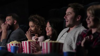 Sevinçle dolu bir grup arkadaş, samimi bir sinemada, kahkaha ve patlamış mısırlarını paylaşan bir filme hayran kalıyor. Parlak gülümsemeleri ve hareketli ifadeleri, sinemanın ve arkadaşlığın sihrini gösteren davetkar bir atmosfer yaratıyor.