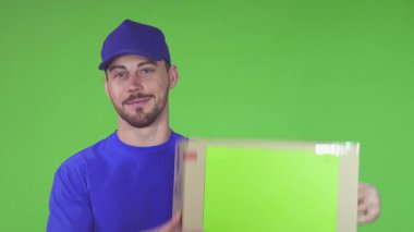 Neşeli sakallı bir teslimatçı, omzundaki karton kutuyu canlı yeşil bir arka planla dengede tutarken sevinçle ışıldıyor. Dostane tavrı ve profesyonel giyimi, paketleri gülümseyerek teslim etmeye olan bağlılığını vurguluyor.