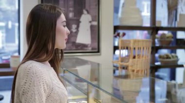 Sıcak bir gülümsemesi olan genç ve çekici bir kadın taze pişmiş bir somun ekmeği tutarken enfes bir fırında başparmağını kaldırıyor. Baştan çıkarıcı hamur işleri ve misafirperver bir atmosferle çevrelenmiş bir şekilde leziz ziyafetlere dalmanın hazzını yaşıyor.
