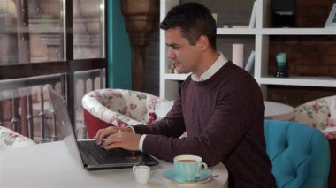 Tarz sahibi genç beyaz bir adam çiçekli sandalyeler ve sıcak bir ortam ile çevrili büyüleyici bir kafede dizüstü bilgisayarıyla çok meşgul. Yanında bir fincan kahveyle, rahatlamış ama üretken bir hava yayıyor, bu sahneyi mükemmel yapıyor.