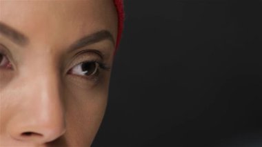 Bu çarpıcı yakın çekim Afrikalı bir kadının özünü yakalıyor canlı kırmızı bir eşarpla süslenmiş büyüleyici gözleri kendine güveni yayıyor. Pürüzsüz, siyah bir arkaplana dayanan portre, onun doğal güzelliğini ve zarafetini ön plana çıkarıyor.