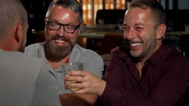 Neşeli, olgun bir adam kadehini kaldırır ve neşeli bir barda arkadaşlarıyla vakit geçirirken neşeyle ışıldar. Sıcak ortam, kahkaha ve dostlukla dolu, dostluğun ve kutlamanın özünü yakalıyor,