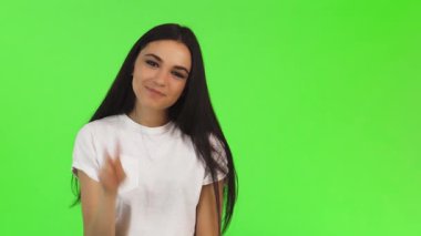 Genç ve güzel bir esmer kadın neşeyle ışıldıyor, neşeli bir şekilde yeşil bir arka plana karşı bir barış işareti gösteriyor. Bulaşıcı gülüşü ve hayat dolu ruhu pozitifliği ve dostluğu, davetkar bağlantıları ve sıcaklığı