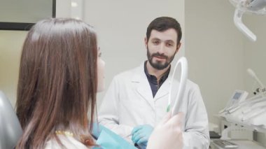 Yetenekli bir erkek dişçi başarılı bir diş tedavisinden sonra aynada onun ışıl ışıl gülüşüne hayran kalarak neşeyle ışıldayan hastasıyla ilgilenir. Bu canlı sahne diş bakımının özünü yakalıyor, bağlantıyı gösteriyor.