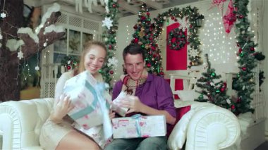 Keyifli bir çift, rahat kazaklar ve eşarplar giyip, neşeli bir şekilde Noel odasında hediyeleri açıyor. Yanıp sönen ışıklar ve çarpıcı bir Noel ağacıyla çevrili kahkahaları havayı dolduruyor, sıcaklığı ve sevgiyi somutlaştırıyor.