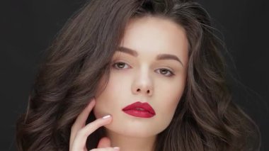 Bu çarpıcı portre, parlak esmer saçlı, çarpıcı kırmızı dudaklı, parlak siyah arka planda kendine güven ve güzellik saçan genç beyaz bir kadını gösteriyor. Kusursuz cildi ve yüzüne dokunuşu saflığın özünü vurguluyor.