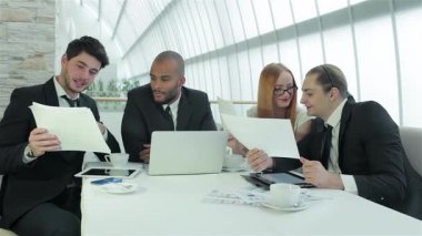 Dört gülümseyen profesyonelin animasyon tartışmaları, fikir ve stratejileri paylaştığı hareketli bir iş toplantısı gerçekleşiyor. Doğal ışıkla dolu parlak ofis ortamı takım çalışmasının ve yeniliğin atmosferini geliştirir.