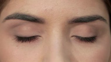 Çekici bir yakın plan, genç ve güzel bir kadının gözlerini yavaşça açarken büyüleyici bakışlarını yakalar. Kusursuz cildi ve narin özellikleri saflık ve tazelik saçıyor, doğal güzellik ve cilt bakımının özünü somutlaştırıyor.