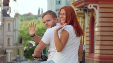 Neşeli bir çift, renkli kentsel mimarinin arka planına karşı kameraya el sallayarak motosiklet sürmekten zevk alır. Gülüşleri mutluluk ve macera saçıyor, yaz özgürlüğünün ve genç romantizminin ruhunu somutlaştırıyor.