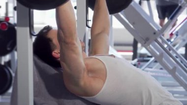 Kararlı, kaslı bir adam modern bir spor salonunda ağırlık kaldırırken ağırlık kaldırıyor. Odaklanmış ifadesi ve tanımlanmış kasları, bu güçlü egzersiz için gereken özveri ve gücü gösteriyor.