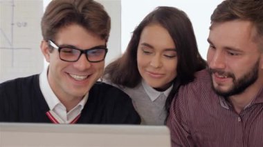 Aralarında gözlüklü esmer bir adam ve sakallı bir adamın da bulunduğu genç profesyonellerden oluşan canlı bir grup, modern bir ofis masasında iş birliği yaparken gülücükler ve şakalar paylaşıyor. Neşeli ifadeleri ve ilgi çekici konuşmaları...