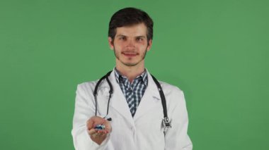 Bakımlı sakalı ve dostane bir gülümsemesi olan çekici bir erkek doktor bir elinde canlı yeşil bir elma, diğer elinde renkli haplar tutuyor. Canlı yeşil renkli bir arka plana karşı çıtır çıtır bir laboratuvar önlüğü giymişti.