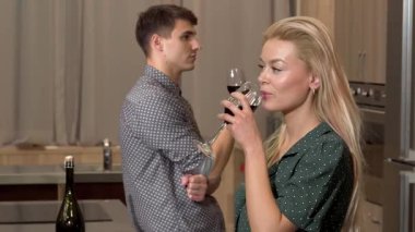 Çekici bir kadın sıcak bir mutfakta şarabının tadını çıkarırken, erkek arkadaşı da ona neşeli bir gülümsemeyle hayran kalıyor. Bu samimi an romantizmin ve bağlantının özünü yakalar. Aşkı ve birlikteliği kutlamak için mükemmeldir.