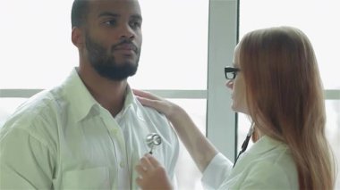 Parlak bir klinikte, odaklanmış bir kadın doktor erkek hastalarının kalp atışlarını dinlemek için hafif bir steteskop kullanır ve kapsamlı bir muayene sağlar. Sıcak atmosfer profesyonel etkileşimlerini vurguluyor.