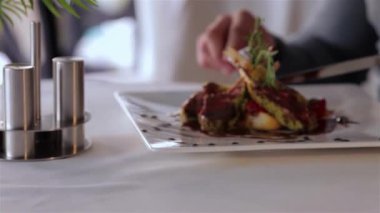 Çok güzel sunulmuş bir gurme yemeğinin yakın plan çekimi taze otlarla süslenmiş taze et sergileri seyirciyi mutfak sanatının tadını çıkarmaya davet ediyor. Sahne, her ısırığın hoş bir patlama vaat ettiği güzel bir yemeğin özünü yakalıyor.