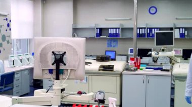 Odaklanmış genç, beyaz önlüklü, laboratuara giren ve heyecan verici bir bilimsel keşfe hazırlanan Kafkasyalı erkek bir laboratuvar çalışanı. Gelişmiş laboratuvar cihazları ve parlayan ekranlarla çevrelenmiş,
