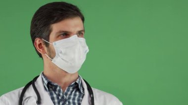 Kendine güvenen beyaz önlüklü ve koruyucu maskeli bir erkek doktor kameraya sıcaklık ve profesyonellik saçıyor. Canlı bir krom anahtar arka planına sahip olan bu dost canlısı sağlık uygulayıcısı, güven ve uzmanlığı somutlaştırmaktadır.