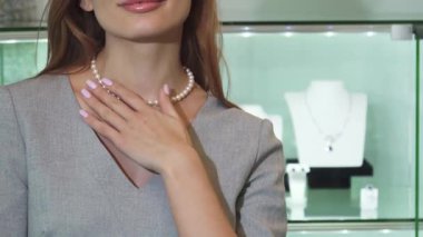 Işıl ışıl kızıl saçlarıyla mutluluk saçan bir kadın zarif inci kolyesine nazikçe dokunurken ışıl ışıl mücevherlerini sergiliyor. Bu büyüleyici sahne lüksün ve kutlamanın özünü temsil ediyor.