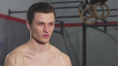 Kararlı genç bir erkek atlet modern bir spor salonunda kettlebell kaldırırken gücünü ve konsantrasyonunu sergiliyor. Keskin fiziği ve yoğun bakışları spor yapmaya ve sağlıklı bir yaşam tarzına olan bağlılığını yansıtıyor.