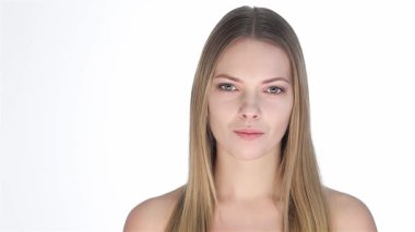 Çekici, sarışın bir kadın parmağını şakayla dudaklarına dayayıp sessiz bir jest yapıyor. El değmemiş beyaz bir arkaplanda cazibe ve cazibe yayıyor. Kusursuz cildi ve nazik gülüşü kendine güven ve zarafet saçıyor. Seyircileri güzellikler dünyasına davet ediyor.