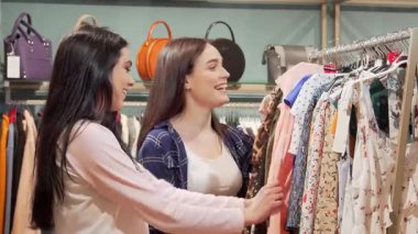 İki şık genç kadın canlı bir giyim mağazasını keşfederek satıştaki renkli elbiseleri tartışıyor. Neşeli ifadeleri ve şakaları arkadaşlığın ve perakende terapinin neşesini somutlaştıran hareketli bir atmosfer yaratıyor.