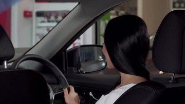 Işıl ışıl bir kadın yepyeni arabasında otururken kendinden emin bir şekilde arabasının anahtarını gösteriyor. Bu canlı sahne, sahip olmanın heyecanını ve şık bir araca önemli bir yatırım yapmanın heyecanını yansıtıyor.