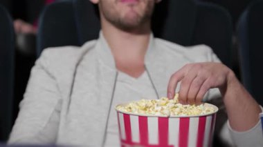 Neşeli bir çift loş bir sinemada rahat bir şekilde oturur, filme dalmışken büyük bir kova patlamış mısır paylaşırlar. Atmosfer heyecanla ve kahkahalarla dolu. Her anın tadını çıkarıyorlar. Etrafı film izleyicileriyle çevrili.