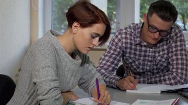 Parlak bir sınıfta, güzel bir kız öğrenci erkek sınıf arkadaşı onun yanında notlar alırken özenle ders kitabını yazar. Bu canlı sahne, akademik adanmışlığın ve işbirliğinin özünü yansıtıyor, öğrenmenin ve