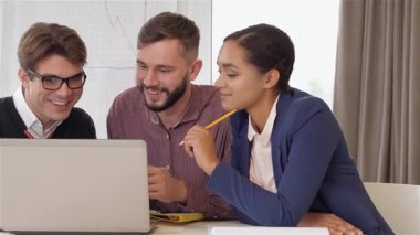 Modern bir ofis ortamında dizüstü bilgisayar ekranını incelerken iki beyaz erkek ve bir siyah kadın odaklanmış bir tartışmaya girişiyor. Gözlüklü çekici esmer adam sohbeti yönetirken, kendine güvenen Afrikalı Amerikalı kadın düşünceli bir şekilde