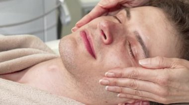 Becerikli eller yüzüne ve şakaklarına nazikçe masaj yaparken mutlu bir adam, onu lüks bir spa merkezinde sükunetle sarıp sarmalıyor. Bu rahatlatıcı deneyim, kendini işine adamış bir masözün profesyonel dokunuşunu gözler önüne sererek rahatlama sanatını ön plana çıkarıyor.