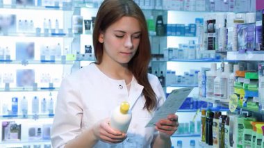 Kendine güvenen genç bir kadın eczacı elinde reçeteyle parlak bir eczanede duruyor ve en iyi ilacı seçiyor. Çeşitli sağlık ürünleriyle dolu renkli raflarla çevrili, profesyonelliği ve ilgiyi somutlaştırıyor.