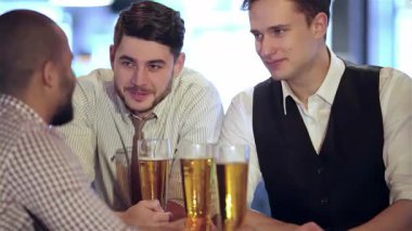 Dört arkadaş, şık günlük kıyafetler giymiş, keyifle bira bardaklarını tokuşturarak TV 'de heyecanlı bir futbol maçı izliyorlar. Canlı atmosfer kahkahalar ve tezahüratlarla dolu, yoldaşlığın özünü yakalıyor ve bir kutlamanın ardından...