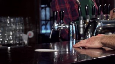 Yetenekli bir barmen köpüklü, altın birayı bardağa doldurur ve hareketli barda hoş bir an yaratır. Sahne, yoldaşlığın ve gevşemenin özünü yakalıyor, barın sıcak parıltısı ve davetkar atmosfer ile...