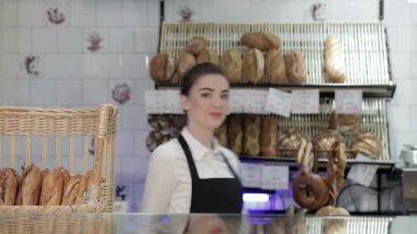 Neşeli genç bir fırıncı, yeni müşterilerini sıcak fırınına yeni pişmiş ekmek ve hamur işleriyle çevrili bir şekilde davet ederken neşeyle ışıldıyor. Sıcak somunların ve tatlı ikramların davetkar aroması havayı doldurur ve enfes bir tat yaratır.