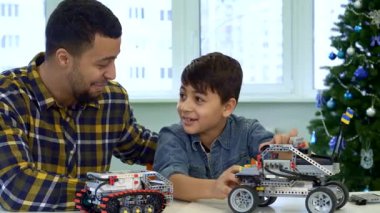 Çekici esmer bir baba ve sevimli oğlu, neşeli bir Noel ağacı ile çevrili, parlak bir masada oyuncak bir SUV ile oynarken kahkahalarını paylaşıyorlar. Yakışıklı Afro-Amerikan adam, neşeli çocuğunu komik hikayelerle meşgul ediyor.