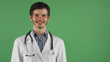 Crisp laboratuvar önlüğü ve steteskop ışınlarıyla kendine güvenen genç, yakışıklı, sakallı bir erkek doktor, canlı yeşil bir arka plana başparmak işareti veriyor. Dostça tavırları güven ve profesyonelliği yansıtıyor. Bu da onu mükemmel bir somutlaştırma yapıyor.