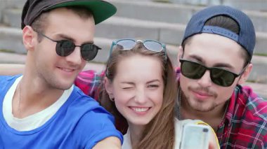 Arkadaşları yanında poz verirken neşeli bir kız kameraya göz kırpıyor. Hepsi şık güneş gözlüğü takıyor. Bu canlı sahne arkadaşlığın ve kaygısız yaz günlerinin özünü yakalıyor, kahkahalarla ve unutulmaz anılarla dolu.