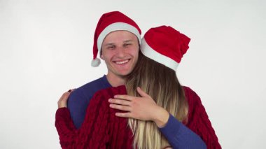 Şenlikli Noel Baba şapkalı neşeli bir genç kız arkadaşını kucaklıyor. Şapkası eşleşiyor, sevgi ve sıcaklık saçıyor. Bu iç açıcı sahne, Noel arifesinde Noel neşesinin özünü yansıtıyor.
