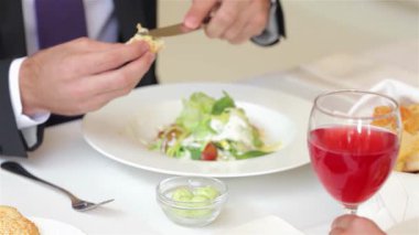 Yakından bakıldığında iyi giyimli bir işadamının canlı bir içkinin tadını çıkarırken taze bir salatayı ustaca kestiği görülüyor. Bu ilgi çekici sahne profesyonel bir atmosfer sergiliyor, iş tartışmaları harika mutfak malzemeleriyle kusursuz bir şekilde harmanlanıyor.