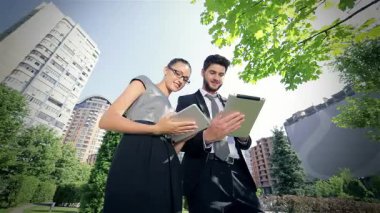 Kendine güvenen bir işadamı ve başarılı bir iş kadını dinamik bir işbirliğine girişerek, canlı kentsel zemin ortasındaki iş sorunlarıyla başa çıkmak için tabletlerden yararlanıyor. Gülüşleri pozitiflik ve hırs saçıyor. Takım çalışmasının gücünü gösteriyor.